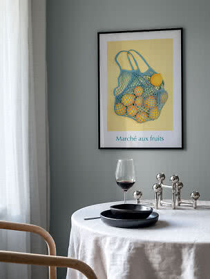 Poster incorniciato con borsa a rete blu piena di limoni su sfondo giallo sopra il tavolo
