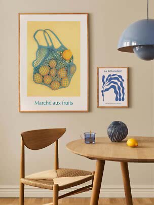 Poster incorniciato con borsa a rete blu piena di limoni su sfondo giallo in un elegante angolo pranzo
