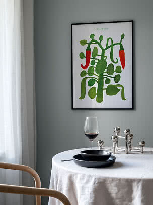 Plakat w ramie z zieloną rośliną chili i czerwonymi papryczkami na szarej ścianie nad stołem