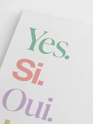 Poster con parole colorate su sfondo bianco, tra cui "Yes.", "Si." e "Oui."