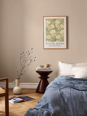 Indrammet William Morris-plakat med blomstermønster over seng i roligt soveværelse