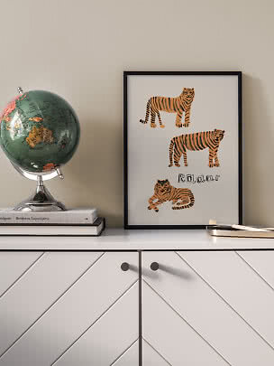 Gerahmtes Poster mit drei Tigerillustrationen auf weißem Hintergrund, auf einer Kommode.