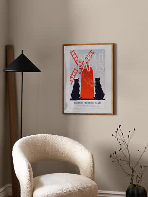 Póster About Paris enmarcado en pared beige sobre silla bouclé blanca junto a lámpara de pie negra