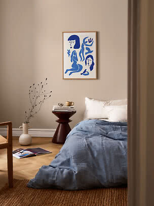 Bedroom with blue bedding and framed abstract blue art print on a beige wall