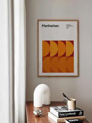 Gerahmtes Manhattan-Poster mit orangefarbenem grafischem Muster über einem Holztisch