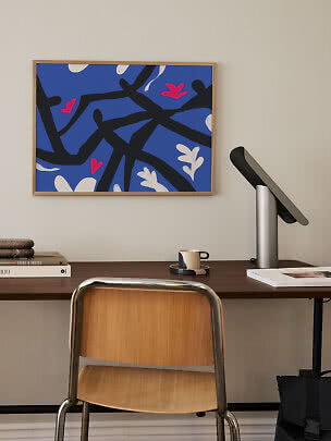 Ingelijste abstracte poster met blauwe achtergrond, zwarte lijnen en witte en roze vormen boven bureau