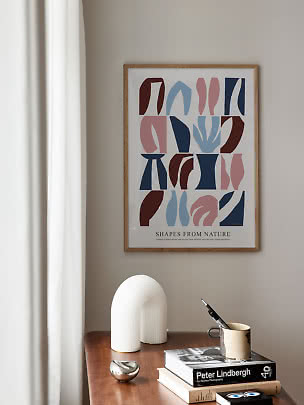 Gerahmtes abstraktes Poster über einem Tisch mit Büchern, Becher mit Stift und weißer Lampe