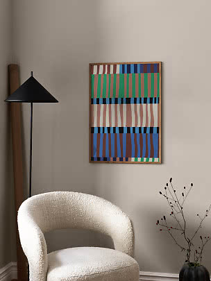Abstract colorful framed wall art above a white armchair beside a black floor lamp