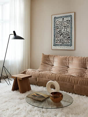 Cozy living room with beige sofa, black floor lamp, glass table and framed wall art