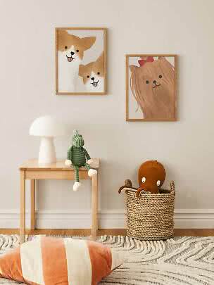 Chambre d’enfant avec deux affiches d’animaux encadrées, table en bois, lampe blanche et panier