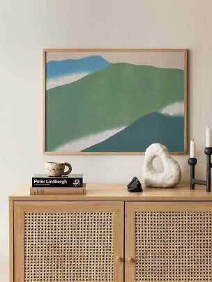 Affiche paysage abstrait encadrée, tons verts et bleus, au-dessus d'un meuble en bois clair
