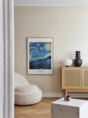 Indrammet Van Gogh Stjernenatten-plakat på beige væg i stue med lænestol og skab