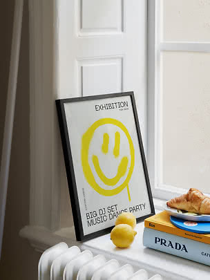 Poster incorniciato con smiley giallo su un davanzale accanto a limoni e libri impilati