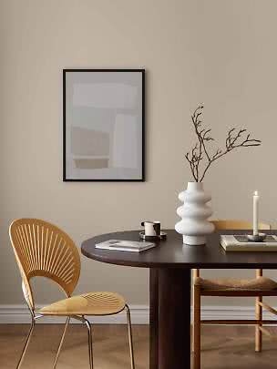 Lámina abstracta enmarcada sobre mesa de comedor con jarrón blanco, rama, vela y silla