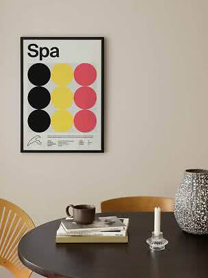 Framed Spa poster with colored circles above a round black table with vase, candle and books