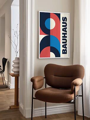 Abstraktes Bauhaus-Poster im weißen Rahmen über einem braunen Sessel in hellem Raum
