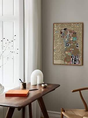 Inramad konstposter med färgstarkt motiv på beige vägg ovanför ett mörkt träbord