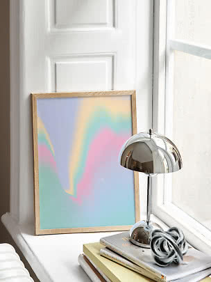 Indrammet abstrakt kunst med pastelfarver på vindueskarm ved siden af kromlampe og bøger