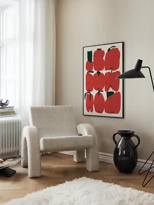Hyggeligt hjørne med bouclé-lænestol, sort gulvlampe og plakat med røde pebre på beige væg