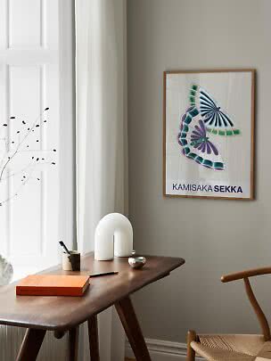 Gerahmter Kunstdruck mit bunten Schmetterlingen über einem Holztisch am Fenster