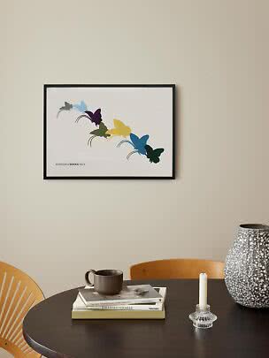 Framed butterfly print with colorful butterflies on a white background above a dining table