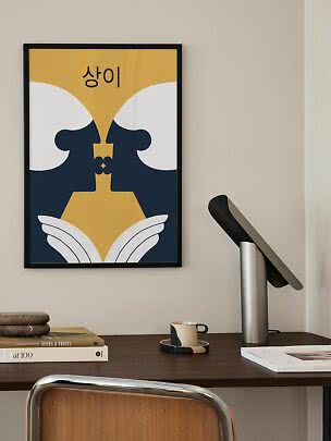 Gerahmtes abstraktes Poster in Gelb, Blau und Weiß mit koreanischem Text über einem Schreibtisch