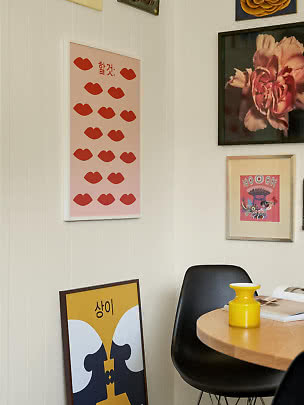 Affiche avec des lèvres rouges sur fond rose, accrochée sur un mur avec d'autres cadres.