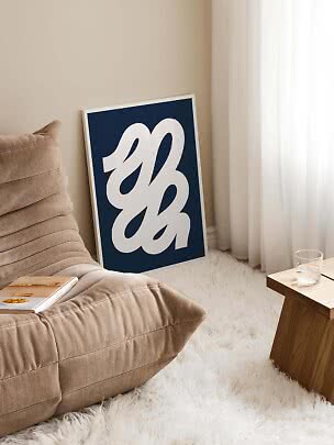 Abstrakt plakat med hvitt motiv på mørkeblå bakgrunn, lent mot stuevegg
