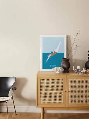 Ingelijste duikposter op licht houten kast met rotandeuren en decoratieve vazen