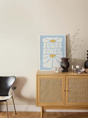 Plakat Flower Power w kolorze niebieskim i żółtym na komodzie z wazonem i dekoracjami