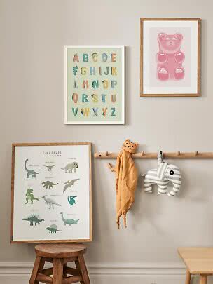 Cameretta con stampe incorniciate, appendiabiti con doudou tigre ed elefante a righe e sgabello in legno