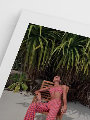 Woman in colorful patterned beachwear reclining in a wooden chair by tropical plants