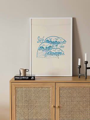 Framed poster with blue wave illustration and 'Surf 1974' text on a wooden cabinet
