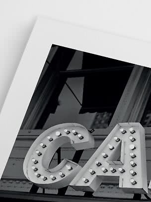 Foto in bianco e nero di un'insegna luminosa con le lettere C e A accanto a una finestra