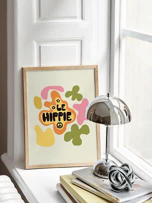 Gerahmtes Retro-Poster „Le Hippie“ auf einer Fensterbank neben einer Chromlampe.