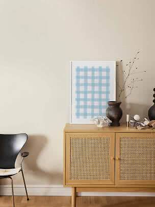 Lyst træskab med fletlåger, vase med grene og blåternet plakat mod beige væg