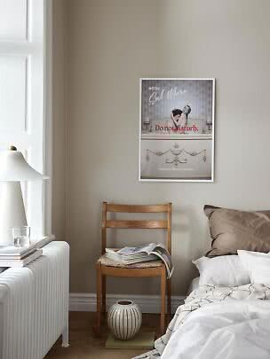 Camera da letto con poster incorniciato sopra sedia in legno, letto, lampada bianca e finestra