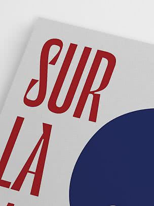 Primer plano de póster con letras rojas sobre fondo claro y un gran círculo azul oscuro