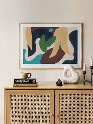 Affiche abstraite encadrée aux formes organiques bleues, vertes, beiges et brunes au-dessus d’un meuble