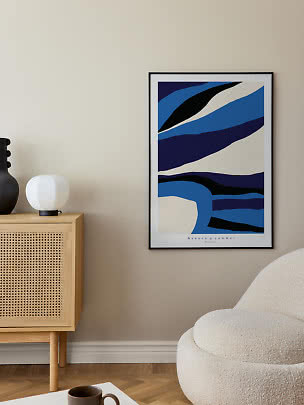 Framed abstract poster in blue, black and cream on a beige wall above a cabinet