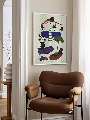 Framed colorful poster with abstract beach scene hanging above a brown armchair in a bright room