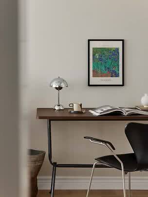 Scrivania con lampada cromata, tazza, libro aperto e poster Van Gogh incorniciato a parete