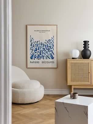 Framed poster with blue botanical illustration above a light wooden cabinet
