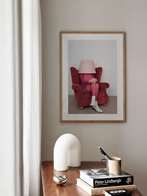Affiche encadrée montrant une personne dans un fauteuil rouge avec un abat-jour en tête