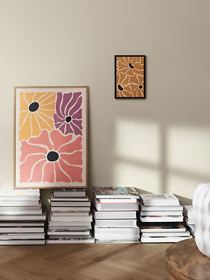 Abstrakta blomsterposters på beige vägg med travar av böcker på golvet