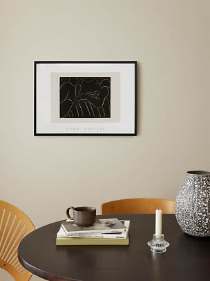 Gerahmter Henri-Matisse-Druck über dunklem Esstisch mit Büchern, Becher, Kerzenhalter und großer Vase