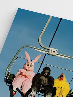 Persone in costume da coniglio, gorilla e pollo su una seggiovia contro il cielo blu