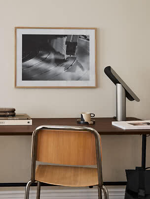 Schreibtisch mit Stuhl, Tischlampe und gerahmtem Schwarz-Weiß-Bild eines Plattenspielers