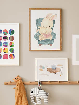 Framed children's poster with two rabbits in a blue armchair reading a book