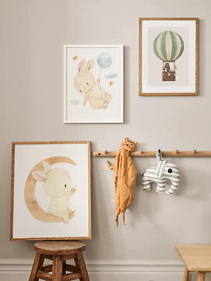 Children’s room wall with bunny prints, hot air balloon art and soft animal hangers on pegs.